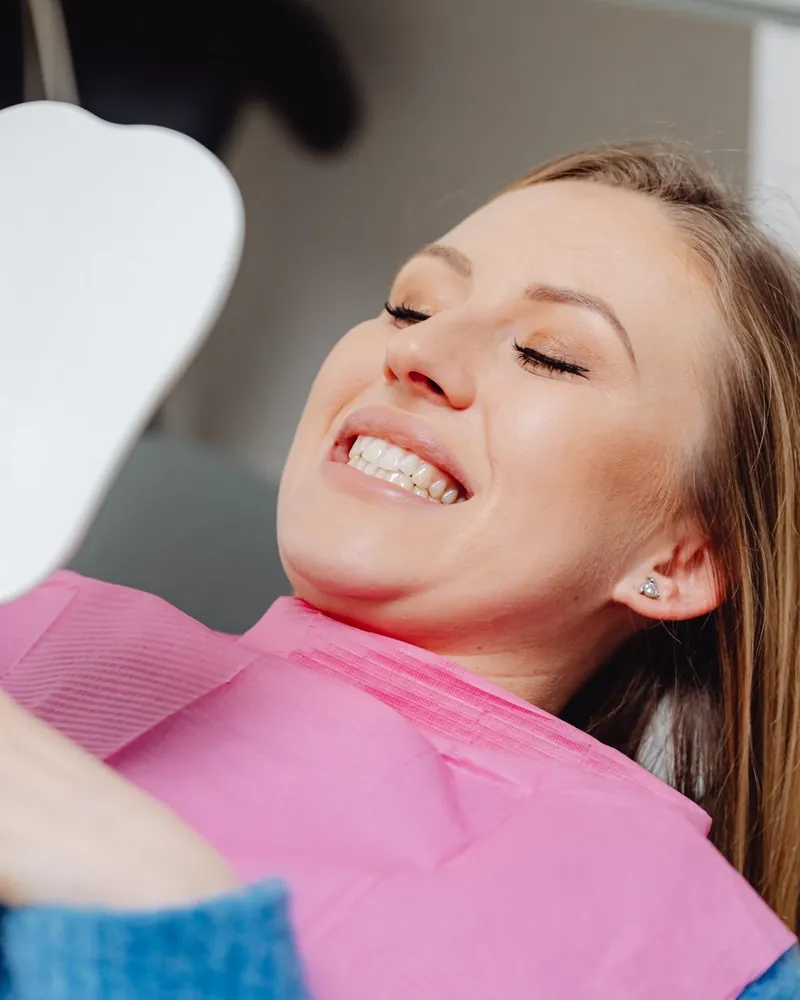 Paciente sonriendo frente al espejo en el sillón dental
